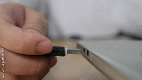Person inserting plug in flashdisk into usb port in laptop personal computer, data transfer device concept