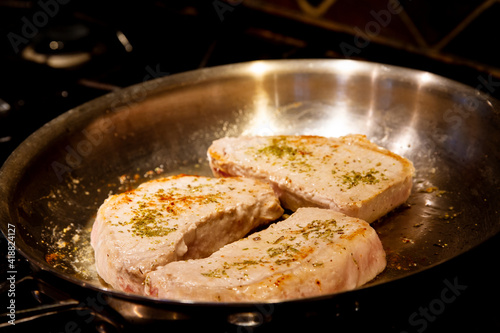 Rosemary seasoned pork loin cuts  searing in a pan; Golden crust on pork loin seared in a pan