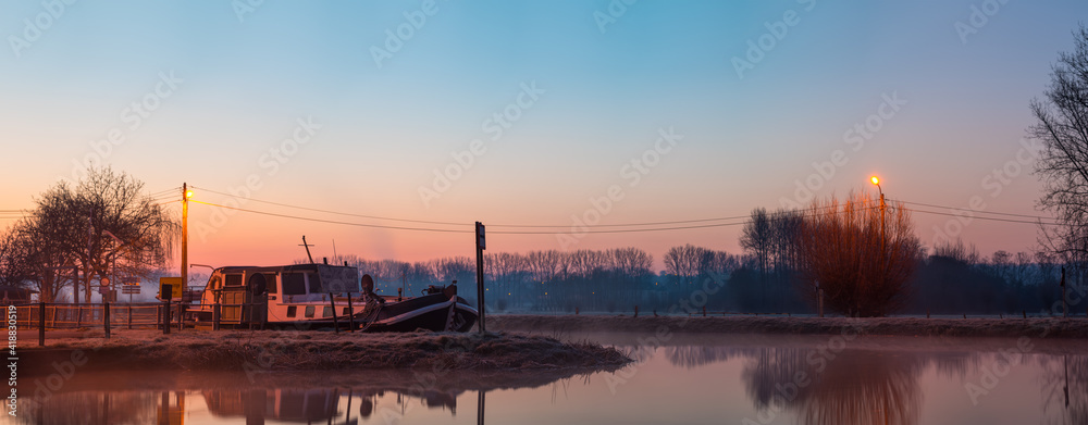An inland vessel lies in the river on a foggy morning