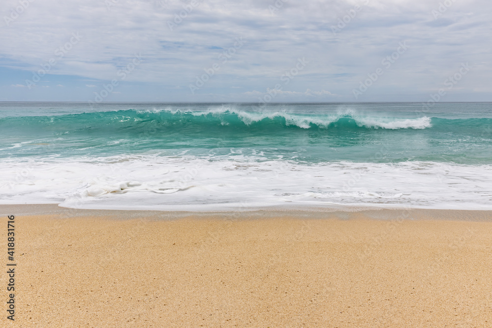 Seascape background. Sandy beach, milky foam waves, blue ocean. Scenic waterscape. Horizon line. Cloudy sky. Nature and environment concept. Daylight. Copy space. Dreamland beach, Bali