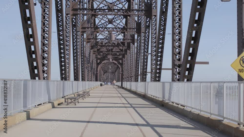 View looking down the center of the Big Four Bridge in Louisville Kentucky with biker passing camera and riding away with push forward.