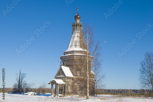 Birch and old wooden Sreteno-Mikhailovskaya church (1655) on February afternoon. Krasnaya Lyaga, Kargopol district. Arakhangelsk region, Russia photo