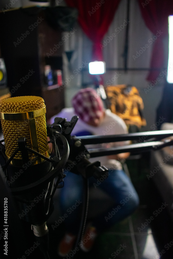 A microphone condenser with a arm, and a guy playing guitat at the background A microphone condenser with a arm, and a guy playing guitat at the background