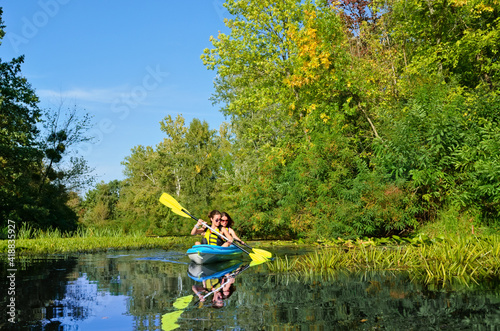 Family kayaking, mother and daughter paddling in kayak on river canoe tour having fun, active weekend and vacation with children, fitness concept
