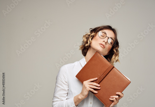 Business woman with open notebook in her hands and glasses on her face, white shirt © SHOTPRIME STUDIO