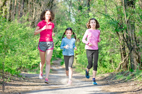 Family running, happy active mother and kids jogging outdoors, run with children in forest, healthy family sport and fitness 