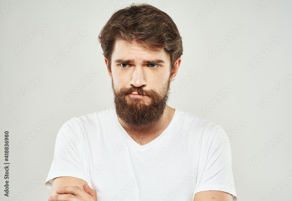 Obraz premium Bearded man in white T-shirt puzzled look sad face cropped look