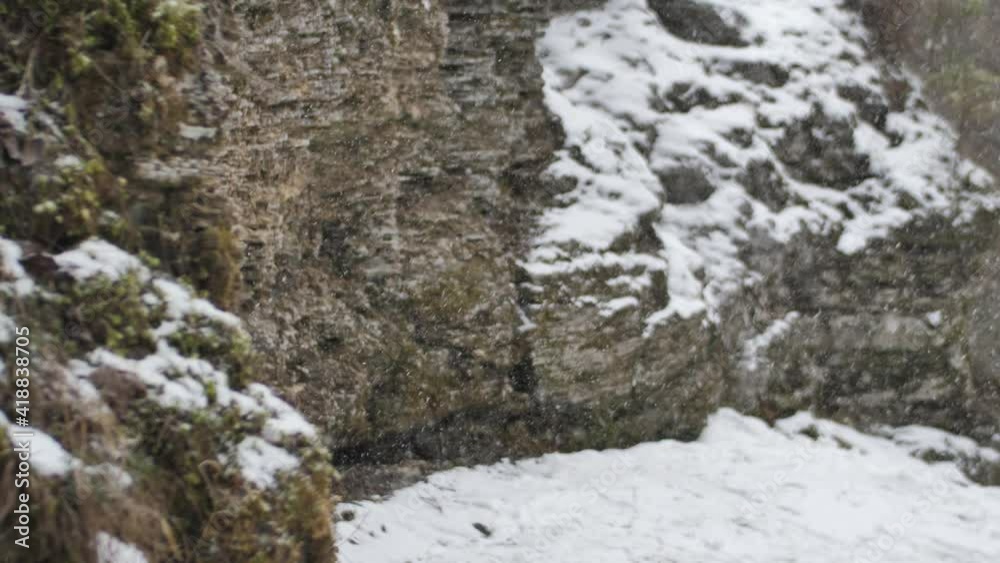 Snow is falling on the rocks. Snowflakes are slowly falling. Winter beauty