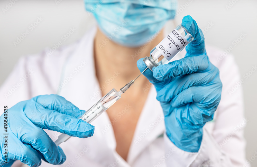 Vial withCOVID-19 vaccine and a syringe with a needle for injections for coronavirus infection in the hand of a doctor in a nitrile glove on a white background. Close-up. Concept fighting Coronavirus Vial withCOVID-19 vaccine and a syringe with a needle for injections for coronavirus infection in the hand of a doctor in a nitrile glove on a white background. Close-up. Concept fighting Coronavirus