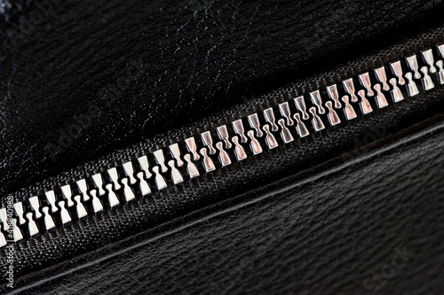 Black leather ladies bag with metal zippers, shot on a white background.