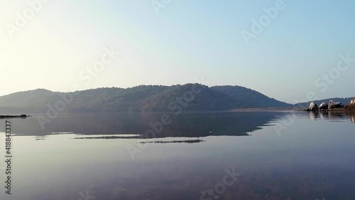 Pristine Water With Densely Forest Valley Reflection During Daytime In Chapoli Dam Reservoir In Canacona, South Goa, India. - Low Angle Shot photo