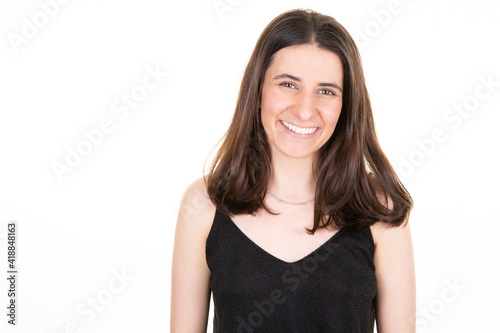 Portrait of cute pretty smiling woman looks in camera over white wall copy space background