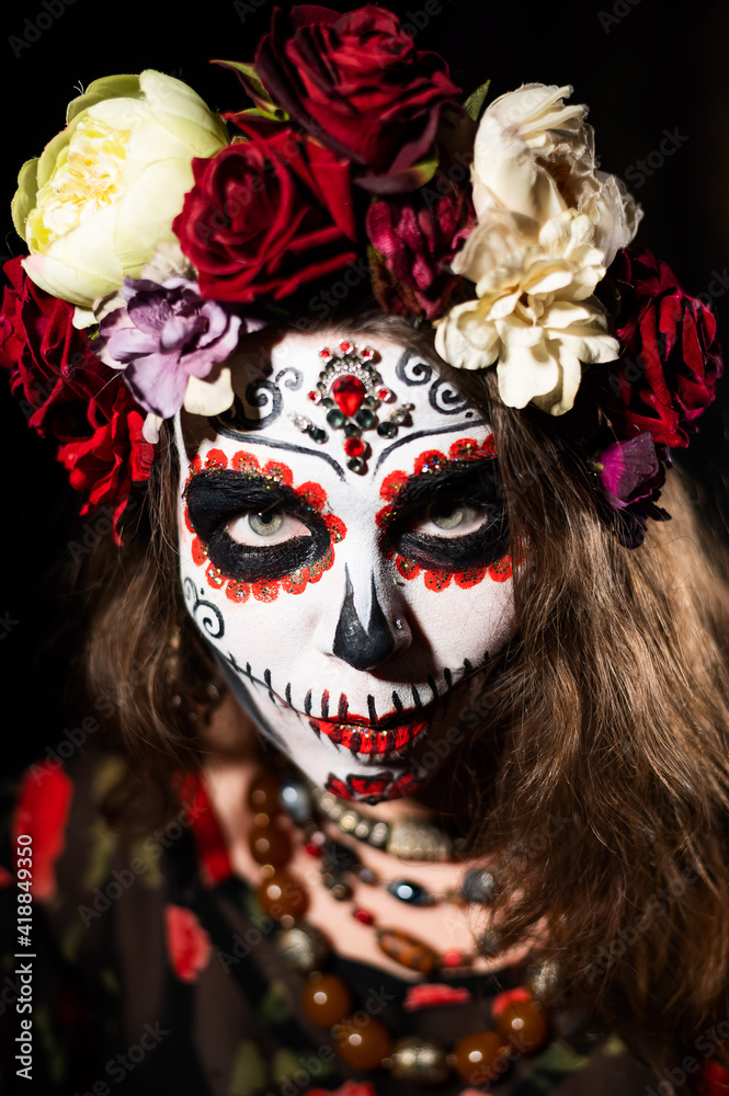 Woman in santa muerte makeup on a black background. Girl wearing traditional mexican holy death costume for halloween.
