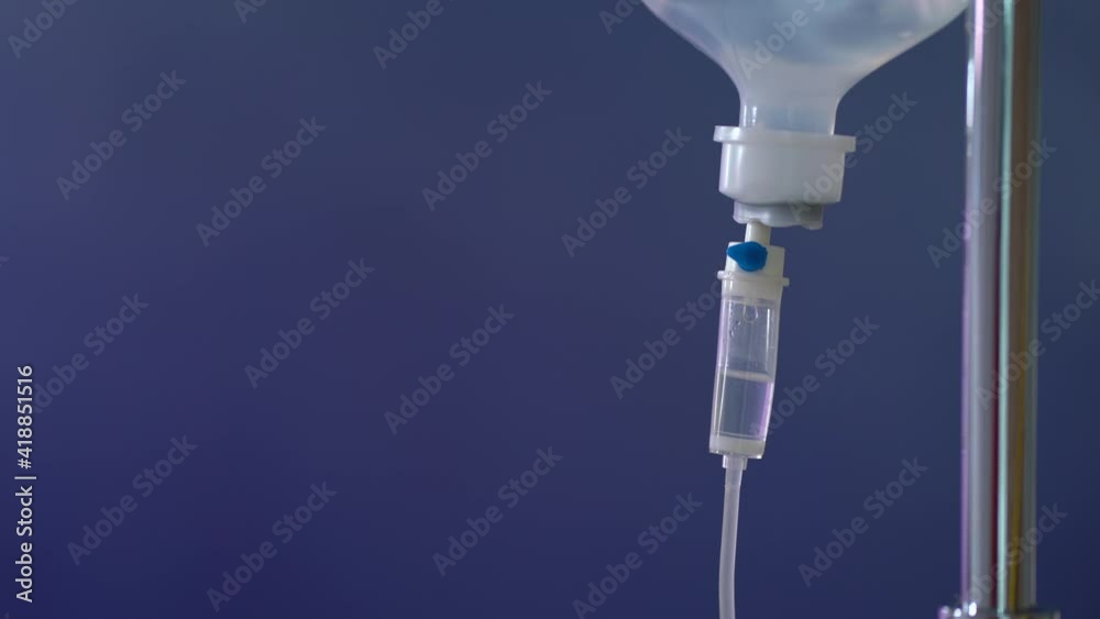 Close up. Saline solution for patient in hospital. IV drip, NSS Intravenous on blue background in operation room.