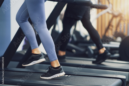 Legs of two girl friends working out on treadmill