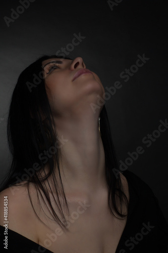 Studio portrait of a brunette in black clothes on a dark background