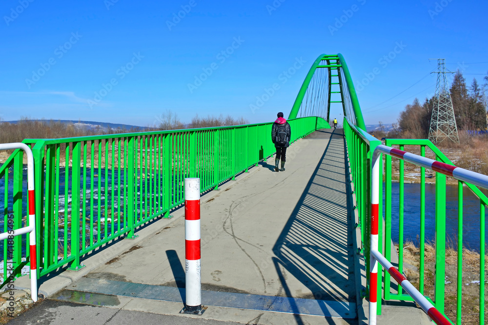 Walking and cycling path across the Poprad river over a bridge in green color, Stary Sacz, Poland