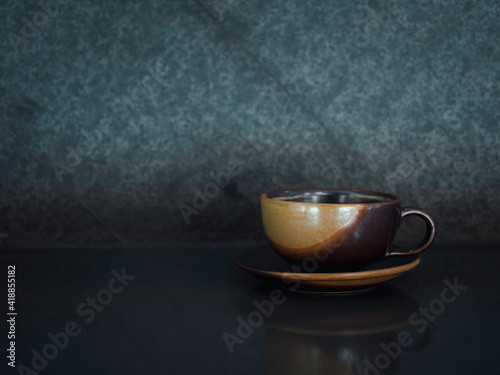 A brown ceramic clay coffee cup with coaster plate.