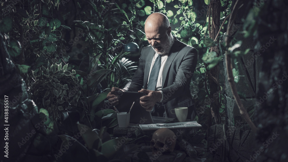 Angry businessman using a computer in the forest