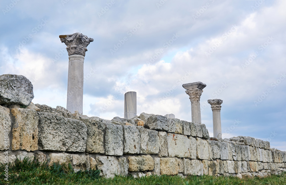 ruins of the wall of antique greek temple with columns against the sky