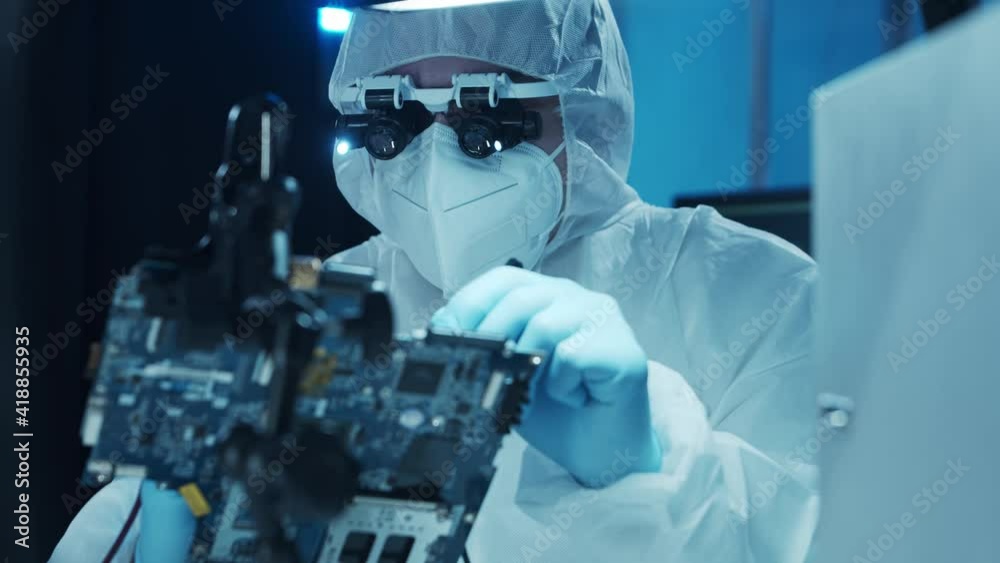Microelectronics engineer works in a modern scientific laboratory on computing systems and microprocessors. Electronic factory worker is testing the motherboard and coding the firmware. Microelectronics engineer works in a modern scientific laboratory on computing systems and microprocessors. Electronic factory worker is testing the motherboard and coding the firmware.