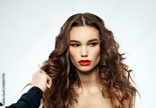 Woman with curly hair grooming naked shoulders and bright makeup