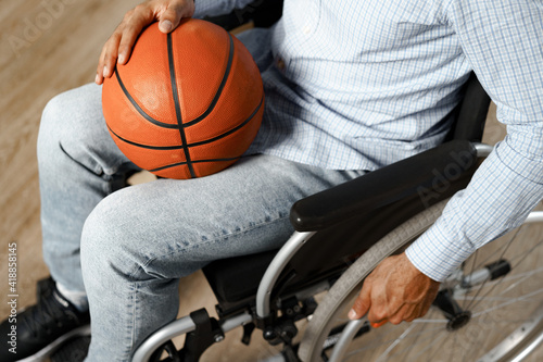 Close up of disabled man sitting in wheelchair and holding basketball ball