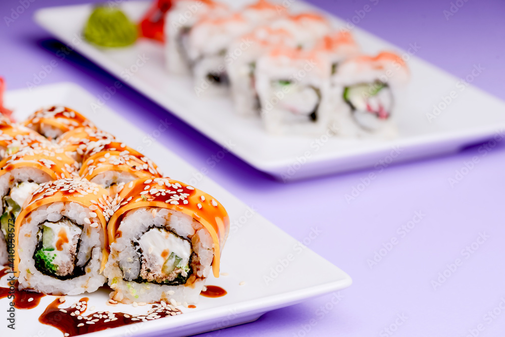 Eel, salmon and tuna sushi with unagi sauce served on a white plate over purple background. Eel, salmon and tuna sushi with unagi sauce served on a white plate over purple background.