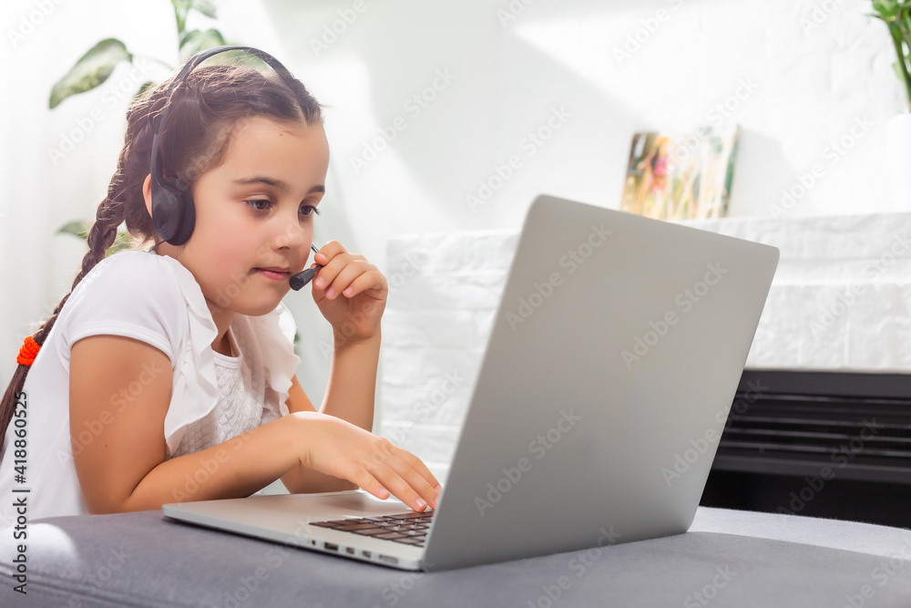 Photo of positive kid girl study remote sit desk table use laptop have online communication lesson with tutor writing report in house indoors Photo of positive kid girl study remote sit desk table use laptop have online communication lesson with tutor writing report in house indoors