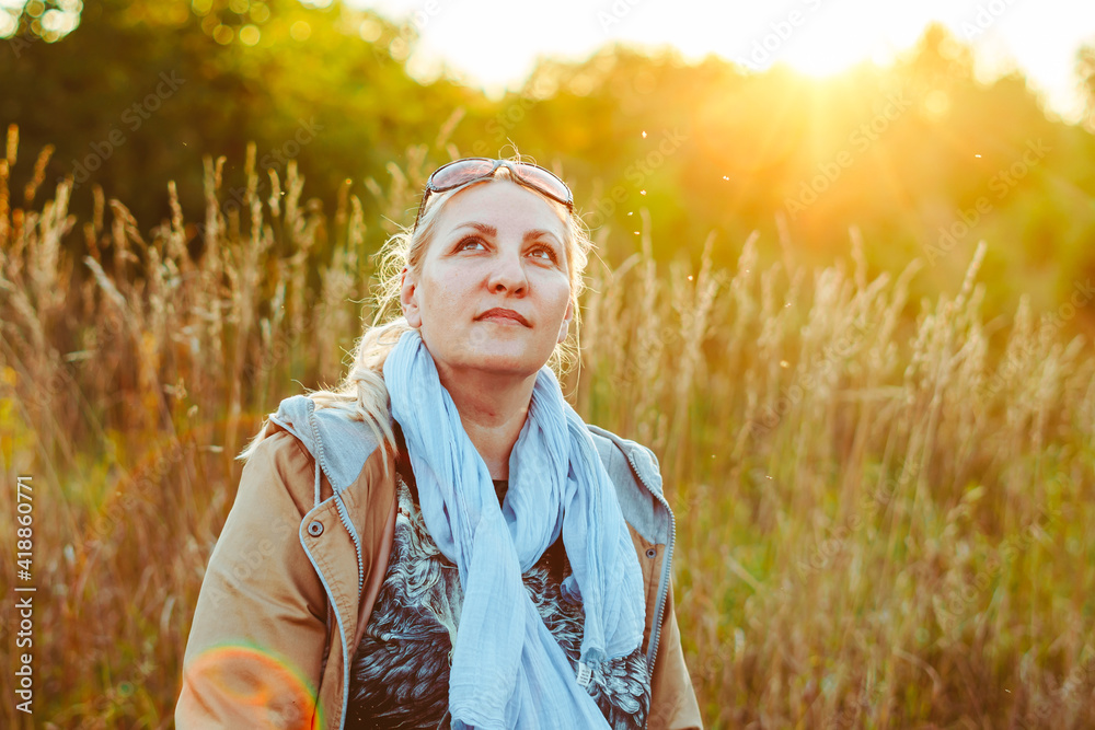 an elderly woman among the grass at sunset