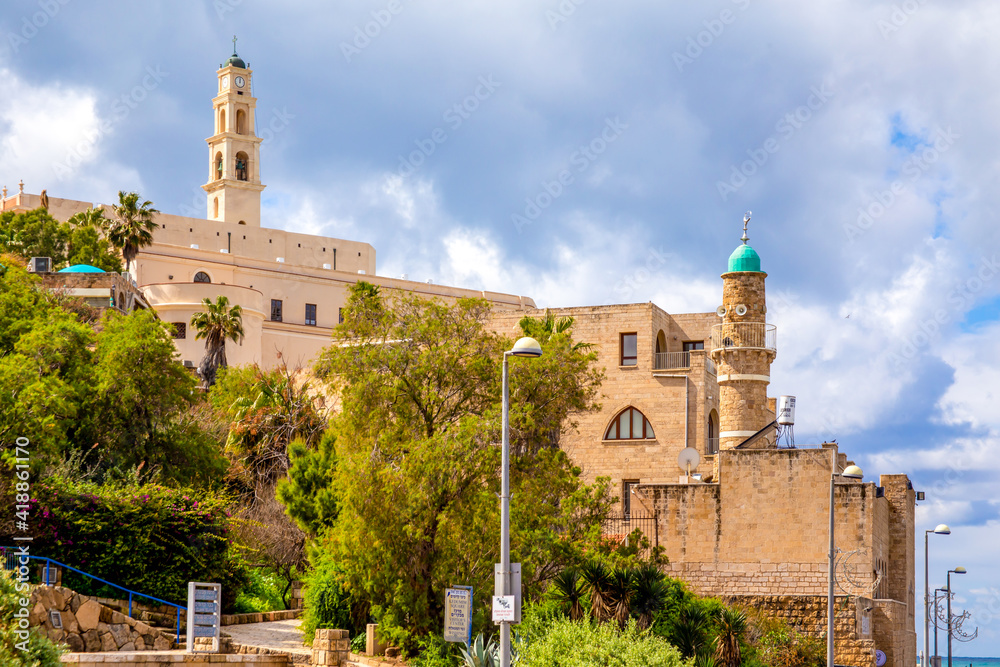 Tel Aviv-Jaffo, Israel - March 04, 2021: View of the St. Peter's Church, bell tower of the Saint Peter Church and the al-Bahr Mosque or Sea Mosque in Old Jaffa in Tel Aviv Yaffo, Israel Tel Aviv-Jaffo, Israel - March 04, 2021: View of the St. Peter's Church, bell tower of the Saint Peter Church and the al-Bahr Mosque or Sea Mosque in Old Jaffa in Tel Aviv Yaffo, Israel