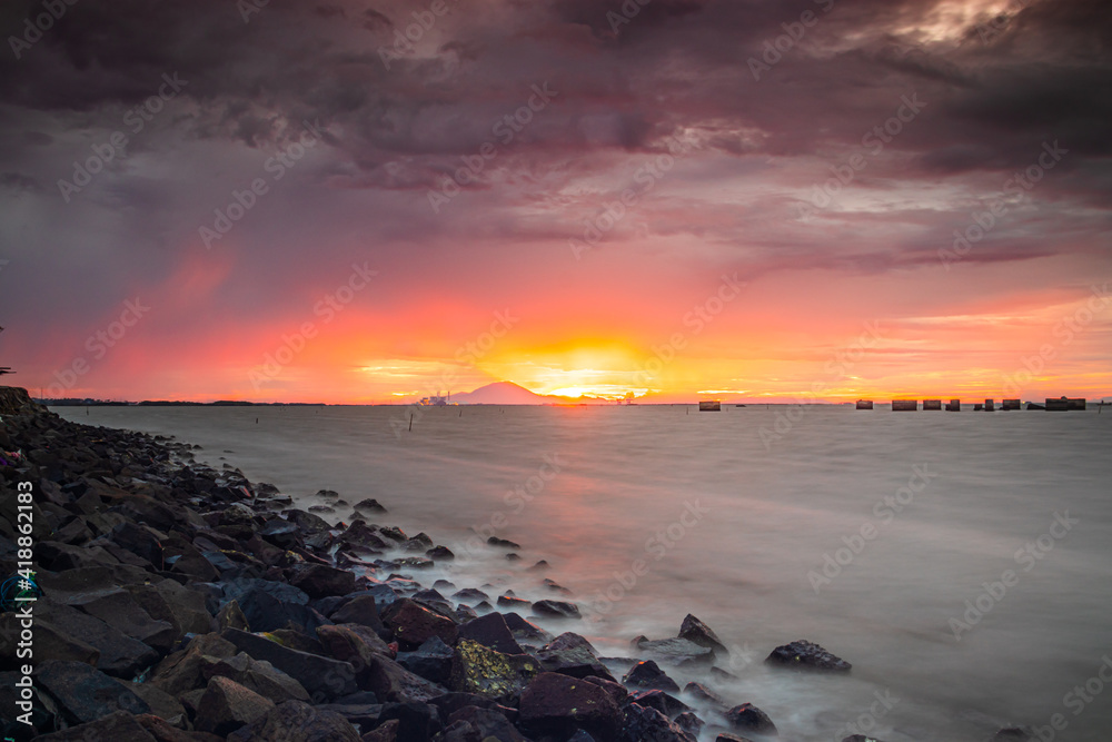 sunset on the beach with a dark cloud