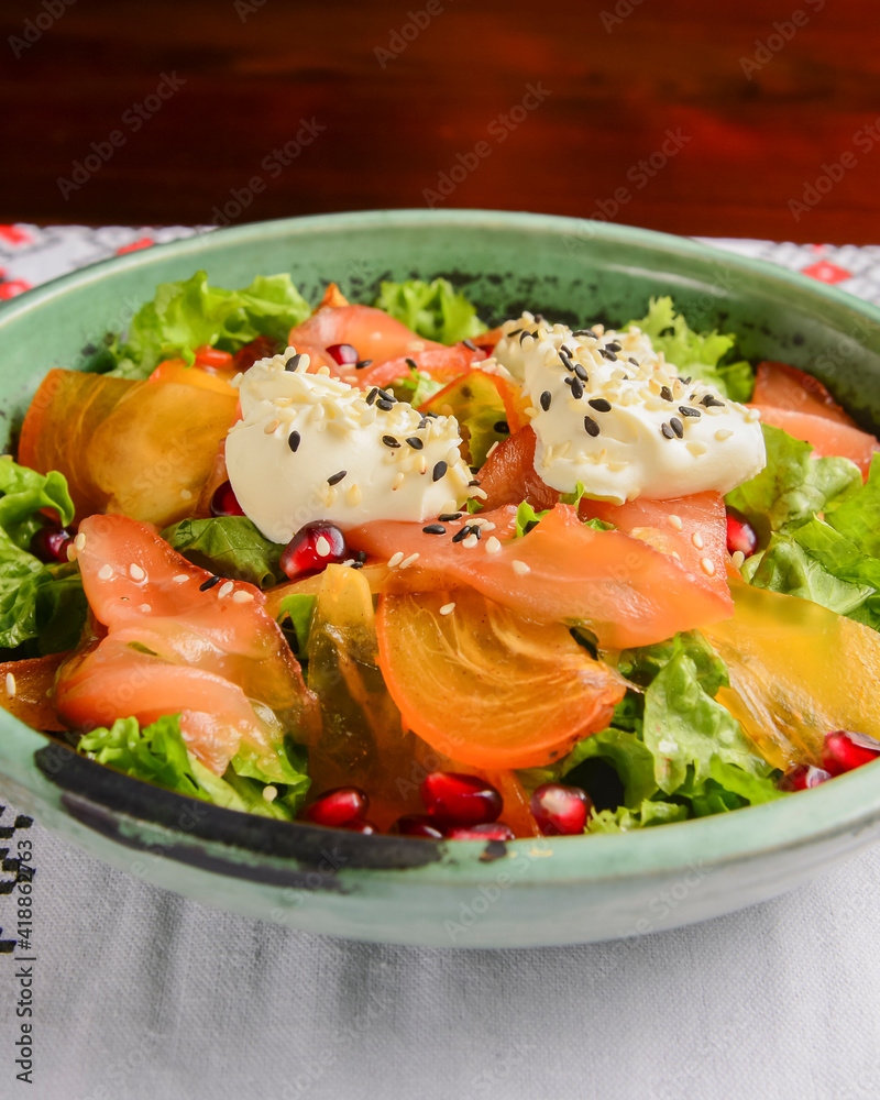 Delicious healthy salmon salad with cheese and pomegranate seeds served in a bowl over traditional Ukrainian tablecloth. Delicious healthy salmon salad with cheese and pomegranate seeds served in a bowl over traditional Ukrainian tablecloth.