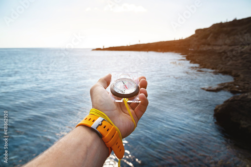 Photography A man's hand with a wristwatch bracelet holds a magnetic compass against the bac