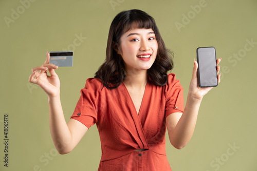 Asian woman holding bank card and holding phone with blank screen