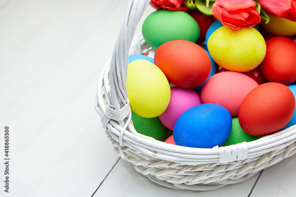 Easter Eggs in basket and spring flowers on white wooden table Easter Eggs in basket and spring flowers on white wooden table