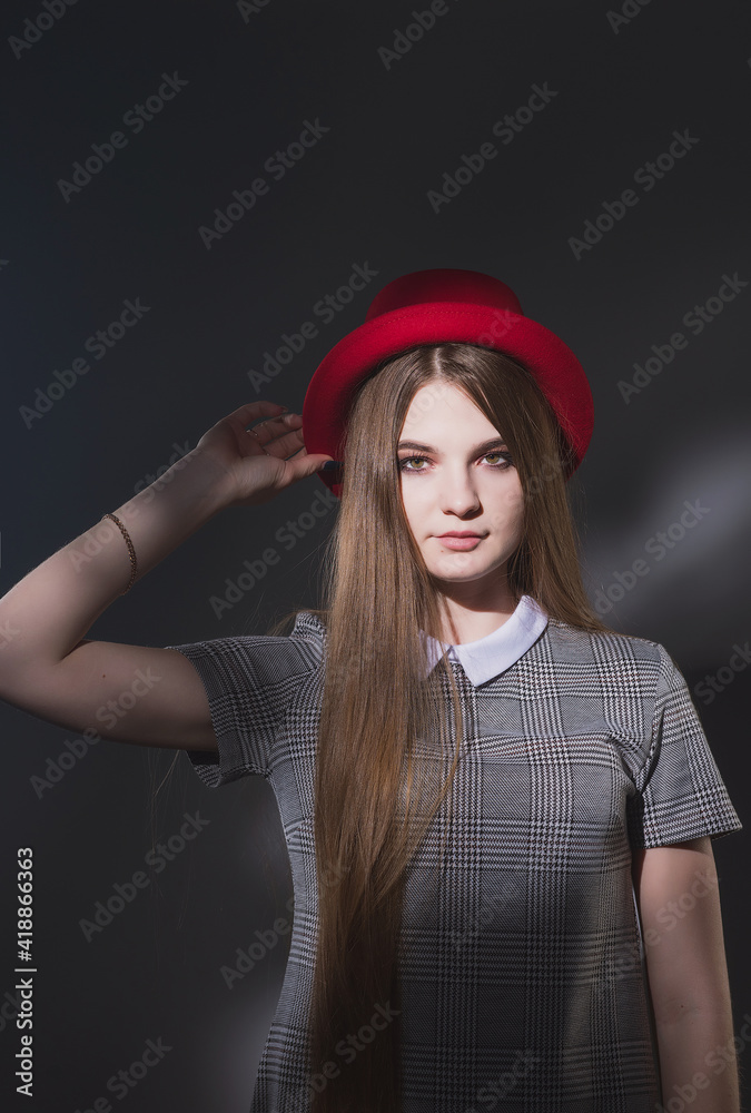 Girl in a gray strict dress in a red hat with narrow brim Girl in a gray strict dress in a red hat with narrow brim