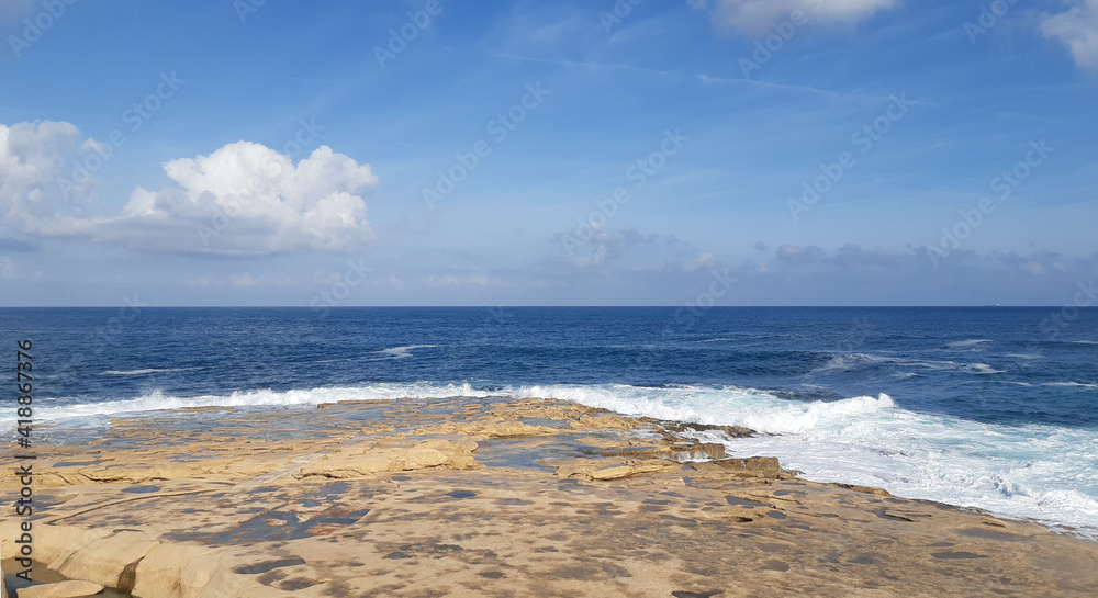 Waves crash against a rocky shore. Sliema, Malta