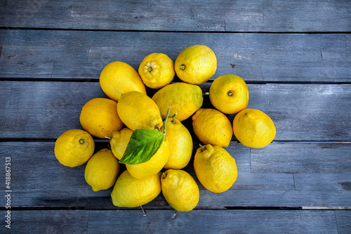 Group of  lemons with one bearing a leaf on a wood table photo