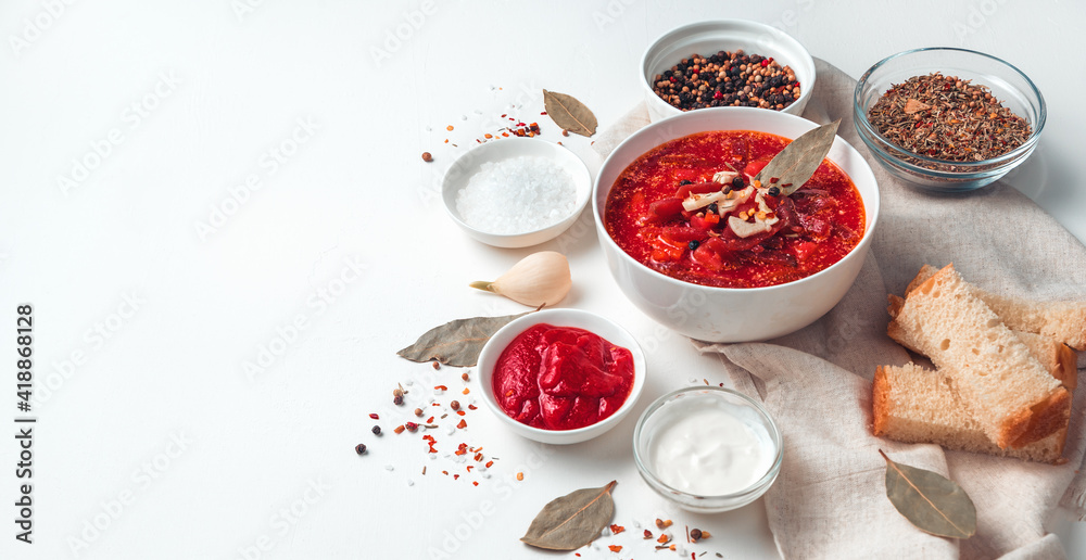 Soup with beetroot, garlic and sour cream on a background of bread and bay leaves, borscht on a light background. Soup with beetroot, garlic and sour cream on a background of bread and bay leaves, borscht on a light background.