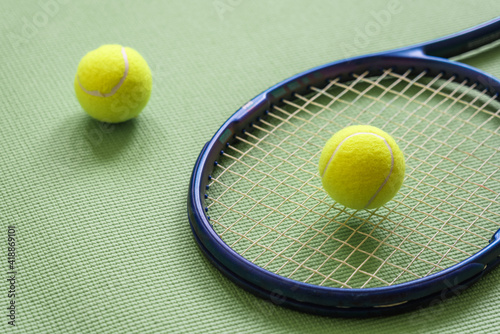 Tennis racket and two tennis balls on green background. Top view, close up. Sport, active lifestyle.