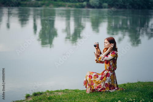 woman in a dress with a camera in nature taking pictures hobby