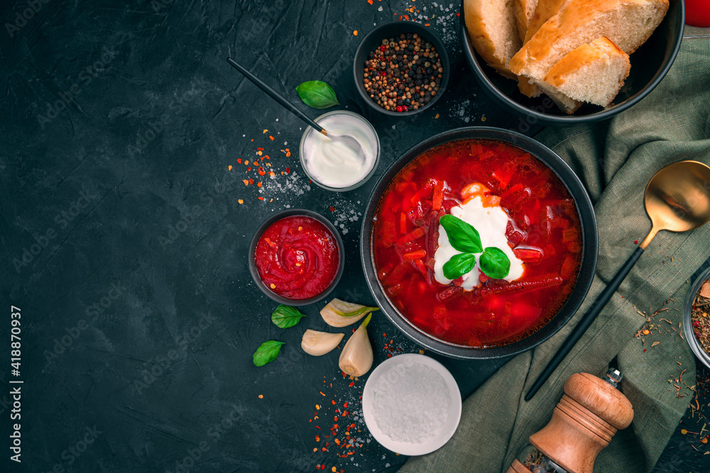 A traditional Russian dish, borscht with sour cream, garlic and spices on a black background.