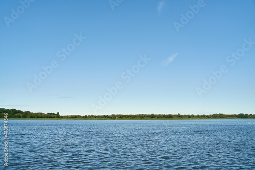 Blue sky over shore of lake on summer day