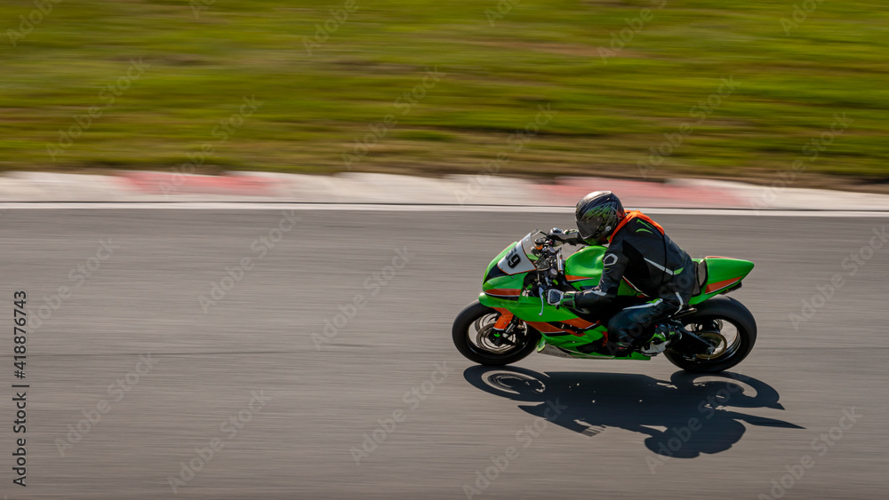 A panning shot of a racing motorbike as it circuits a track.