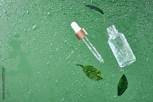 Beauty cosmetic lotion serum bottle and and pipette. Treatment skincare concept with leaves and water drops background