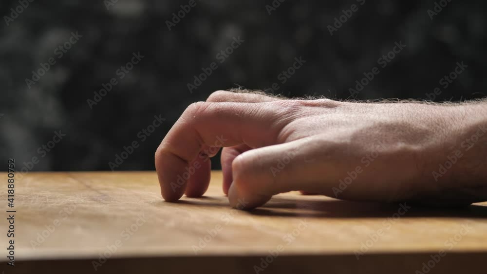 A male hand scratches a board with its nails. A disturbing scene, dramatic light, pain, suffering, problems, violence, a crime story. A male hand scratches a board with its nails. A disturbing scene, dramatic light, pain, suffering, problems, violence, a crime story.