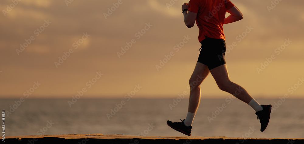 Shot of fit man running along the ocean shore in morning. Healthy male jogging on the beach