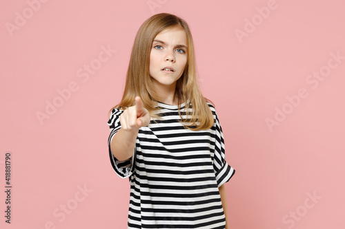 Little blonde serious strict kid nice girl 12-13 years old wearing striped oversized t-shirt point index finger camera on you isolated on pastel pink background children. Childhood lifestyle concept.