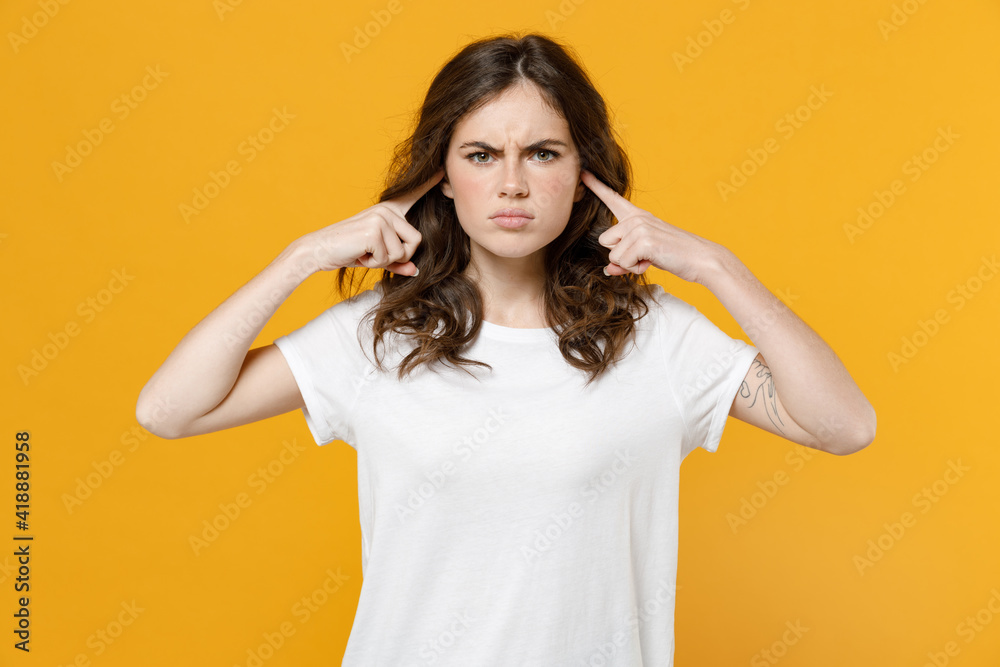 Young serious indignant stressed irritated eueropean caucasian student woman 20s in white basic casual t-shirt look camera cover ears with hands forehead isolated on yellow background studio portrait. Young serious indignant stressed irritated eueropean caucasian student woman 20s in white basic casual t-shirt look camera cover ears with hands forehead isolated on yellow background studio portrait.